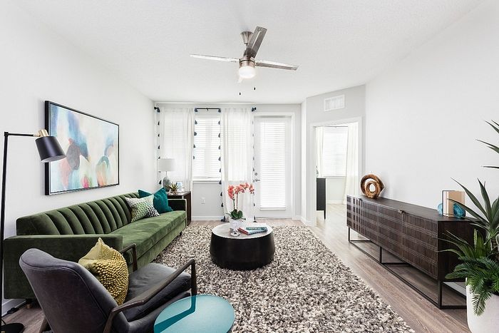 Chic living room with a modern design featuring a plush green sofa, cozy armchair, and stylish decor complemented by natural light.