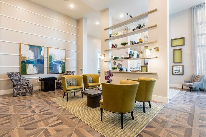 Stylish apartment lounge featuring modern decor, vibrant yellow chairs, geometric patterned flooring, and elegant wall art.