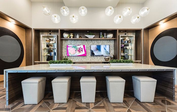 Modern communal area featuring a sleek island counter with elegant pendant lighting, plush seating, and decorative shelving for a stylish and inviting atmosphere.