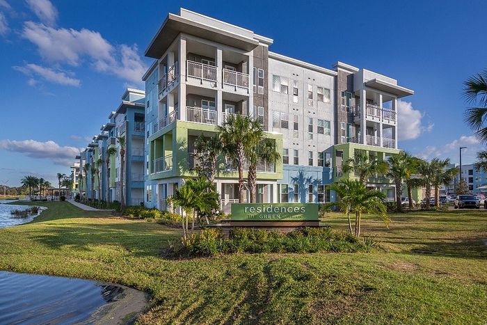 Contemporary waterfront apartment complex with modern balconies, lush landscaping, and serene surroundings at Residences The Green.