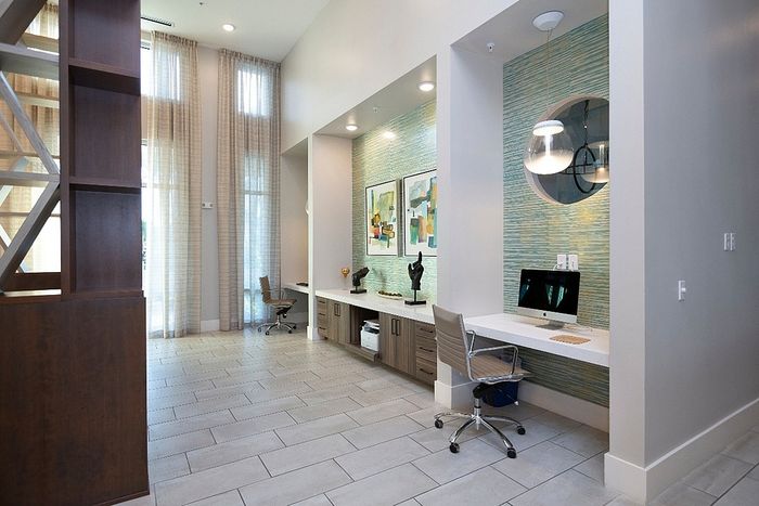 Elegant home office space with high ceilings, modern decor, and ample natural light, featuring stylish workstations and chic artwork for a productive environment.