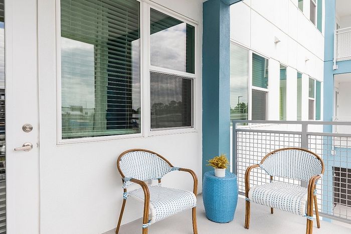 Chic balcony area with two stylish chairs and a vibrant blue side table, perfect for relaxation and enjoying the view.