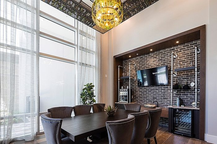 Elegant dining area with a modern chandelier, brick accent wall, and sleek glassware display, exuding sophistication and style.