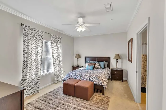 Inviting bedroom with elegant decor, featuring a plush bed, stylish lamps, and ample natural light.