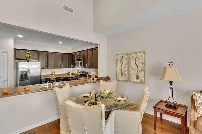 Elegant kitchen and dining area with sleek dark cabinets, a stainless steel fridge, and a cozy round glass table set for four.