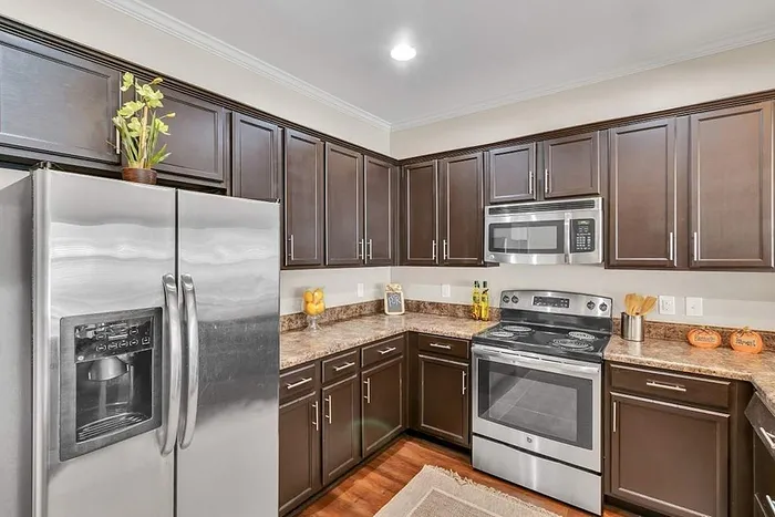 Contemporary kitchen with sleek stainless steel appliances, rich dark wood cabinets, and elegant marble countertops.