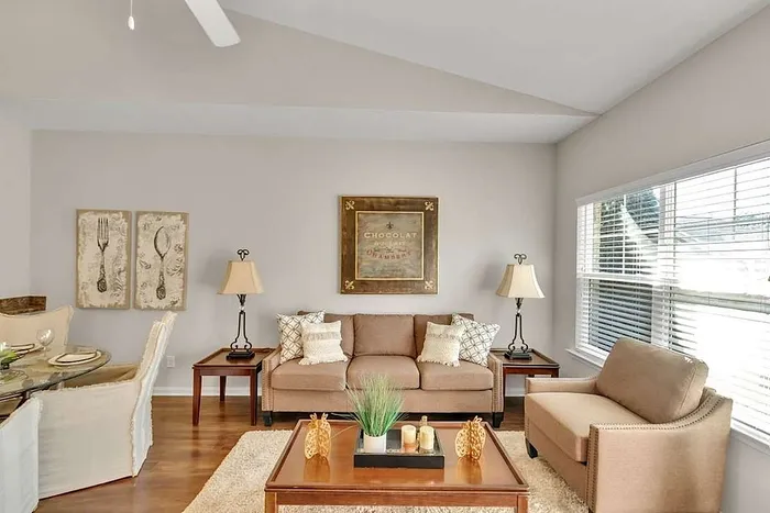 Inviting living room with modern decor, cozy beige sofas, and abundant natural light from large windows.