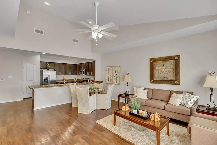 Inviting open-concept living room and kitchen with elegant hardwood floors, modern appliances, and cozy seating area.