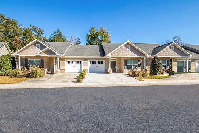 Charming duplex with inviting front porches, two-car garages, and manicured landscaping in a serene neighborhood.