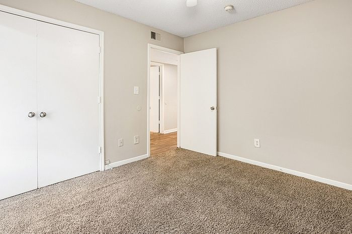 Cozy carpeted bedroom with ample closet space and modern white doors, perfect for a peaceful retreat.