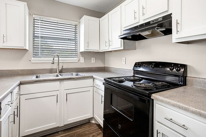 Modern kitchen with sleek black appliances, ample white cabinetry, and elegant countertops, filled with natural light.
