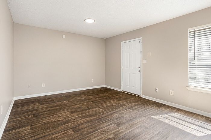 Modern apartment interior featuring elegant wood flooring, ambient natural light, and a crisp, clean entry door.