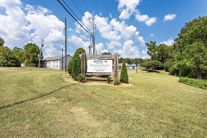Welcome to Bessemer Place Apartments, nestled in lush greenery with a picturesque sky backdrop, offering a serene and inviting atmosphere.