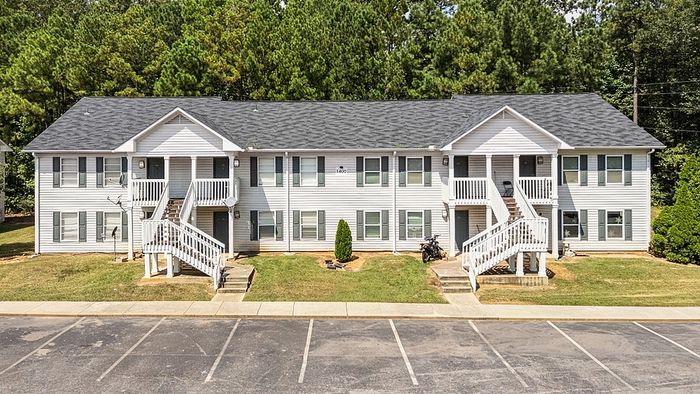 Charming duplex apartment building with inviting front porches and lush greenery, showcasing a blend of modern design and comfort.
