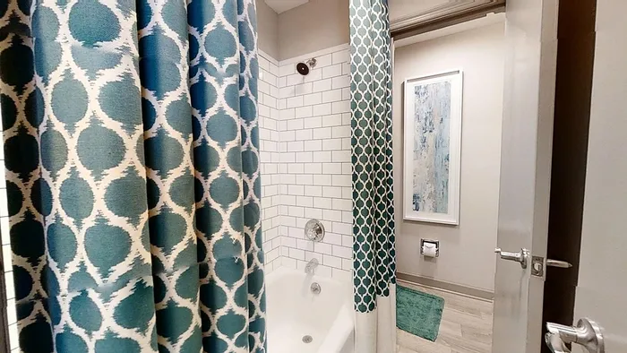 Chic bathroom featuring stylish geometric shower curtains, modern tile backsplash, and elegant wall art.