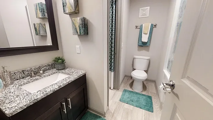 Elegant bathroom featuring modern granite countertop, stylish dark wood vanity, and artful decor with turquoise accents.
