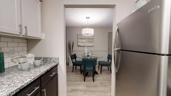 Modern kitchen with granite countertops leading to an inviting dining area featuring elegant seating and stylish decor.