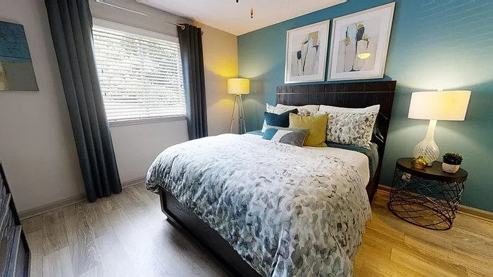 Charming bedroom with modern decor, featuring a plush bed, elegant bedside lamps, and a large window allowing natural light to brighten the space.