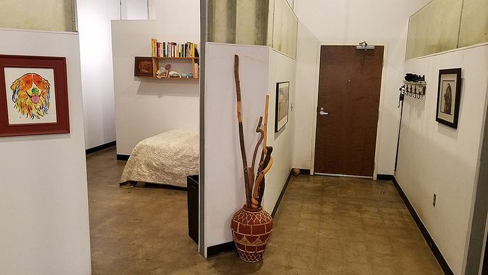 Chic apartment entryway with stylish decor, featuring a cozy bedroom nook and vibrant wall art, blending modern design with warm, inviting elements.