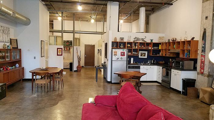 Chic open-plan loft with industrial design, featuring a cozy seating area, stylish kitchen, and modern dining space.