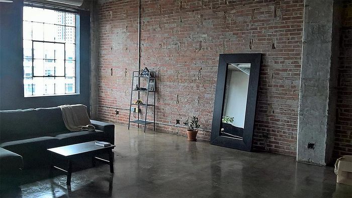 Sophisticated loft-style apartment with exposed brick walls, large windows, and an elegant open space living area.