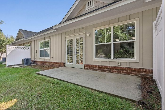 Charming exterior view of a cozy apartment featuring a private patio and lush green lawn, perfect for relaxing outdoors.