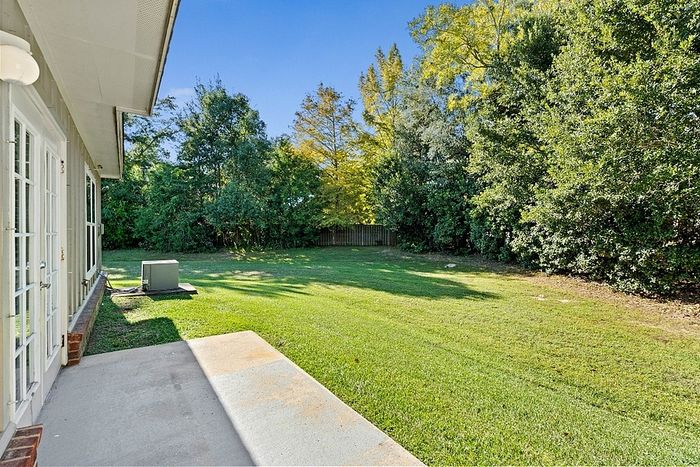 Charming backyard view with lush greenery, expansive lawn, and modern patio area.