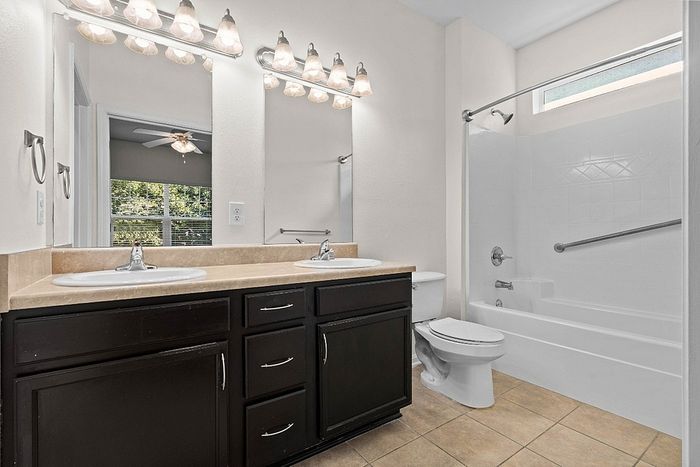 Elegant bathroom with double sinks, modern lighting, and a pristine bathtub in a bright, airy space.