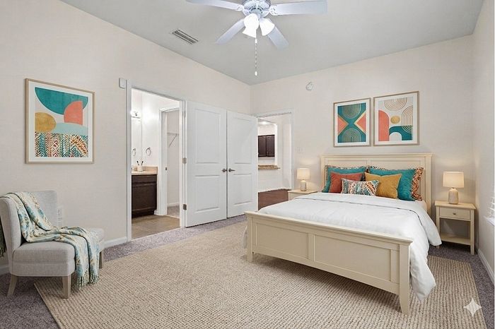 Bright and spacious bedroom featuring elegant decor, a cozy bed, and stylish artwork, leading to an en-suite bathroom.