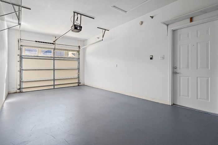 Spacious and bright garage with sleek finishes, featuring a modern automatic door and ample storage potential.