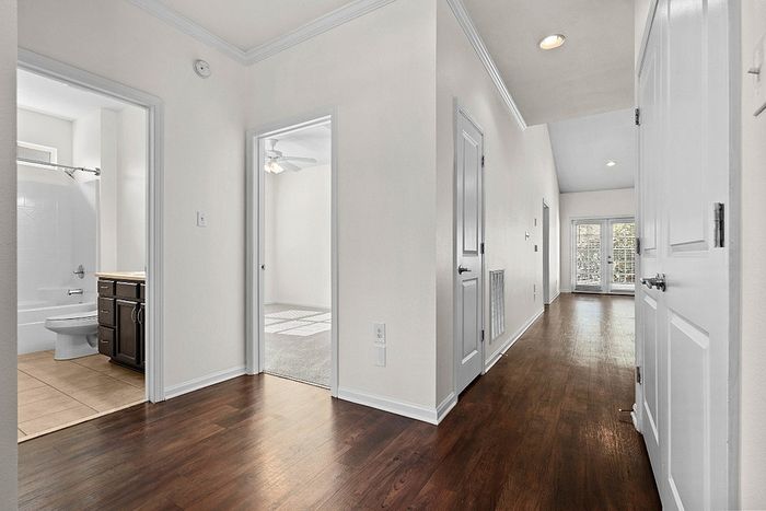 Inviting apartment interior with polished hardwood floors, bright hallway leading to cozy bedroom, and elegant bathroom with modern fixtures.