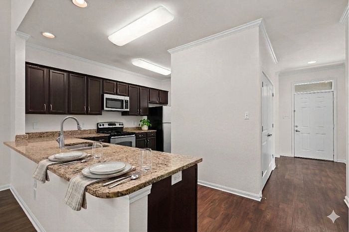 Modern kitchen with sleek dark cabinets, granite countertops, and a cozy breakfast bar in a bright, open space.