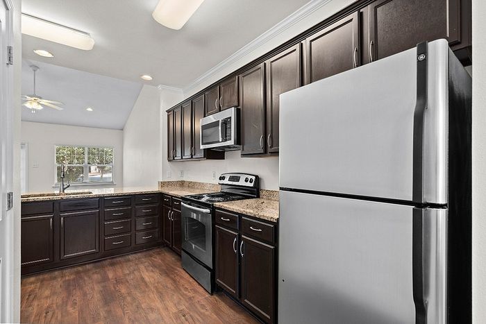 Modern kitchen design featuring sleek stainless steel appliances, dark wood cabinets, and elegant granite countertops, perfect for culinary enthusiasts.