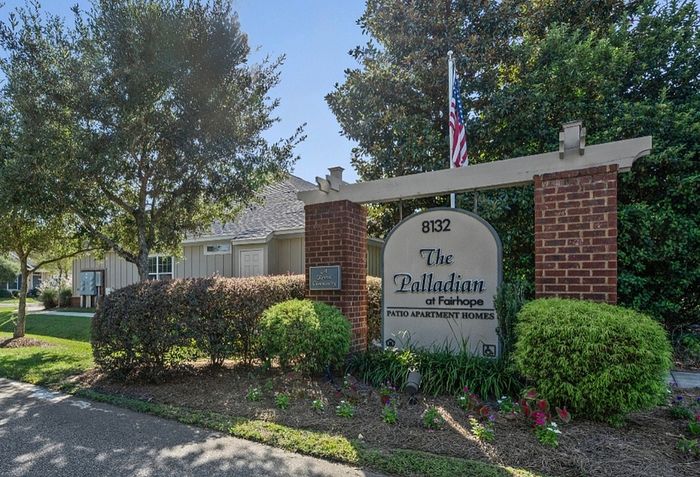 Charming entrance to The Palladian at Fairhope, featuring lush greenery and a welcoming atmosphere.