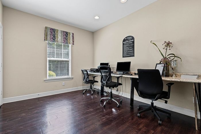 Bright and inviting home office with a sleek workspace featuring modern computers, stylish chairs, and vibrant decor against rich wood flooring.