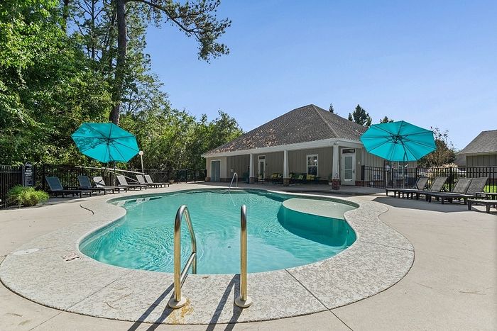 Charming outdoor pool area with turquoise umbrellas and modern lounge chairs, surrounded by lush greenery for a relaxing retreat.