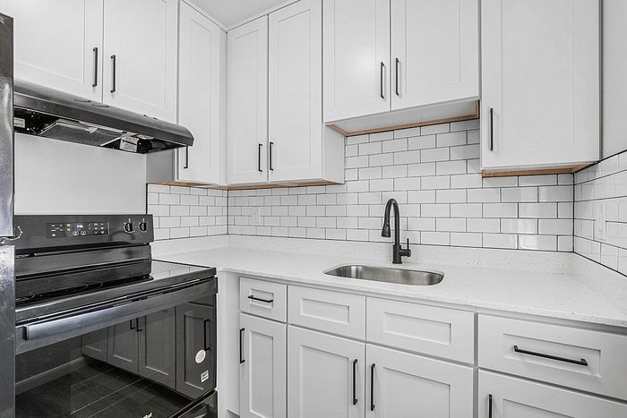 Elegant kitchen with modern black appliances, sleek white cabinets, and stylish subway tile backsplash.