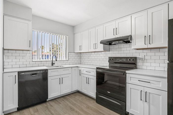 Modern kitchen with sleek white cabinetry, black appliances, and elegant subway tile backsplash.