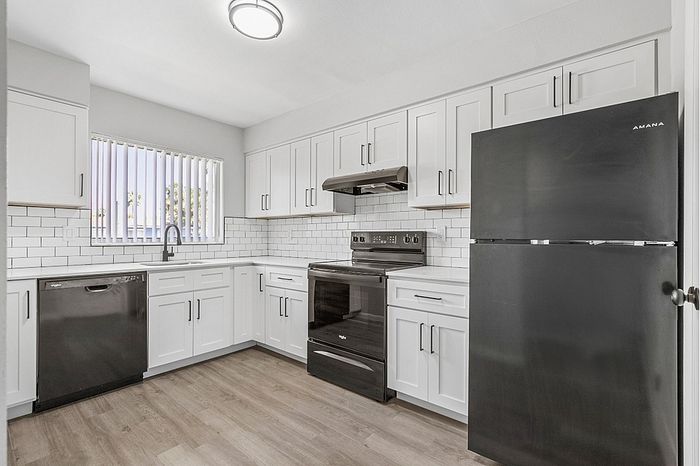 Bright modern kitchen featuring sleek black appliances, white cabinetry, and stylish subway tile accents.