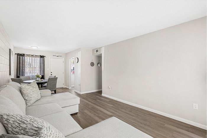 Bright and inviting living room featuring a stylish grey sectional sofa, elegant dining table, and chic decor accents.