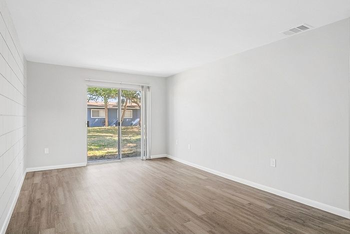 Bright and airy living space featuring hardwood flooring and large sliding glass doors opening to a serene outdoor view.