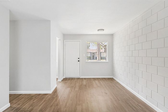 Bright, open-concept living area with modern hardwood floors and chic textured walls, offering abundant natural light.