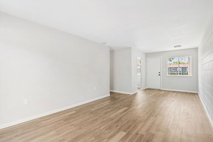 Inviting apartment interior featuring elegant hardwood floors, bright white walls, and abundant natural light from large windows.