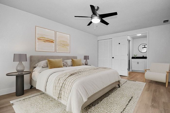 Elegant bedroom retreat featuring a plush bed, cozy lighting, and stylish artwork, with an en-suite bathroom and modern ceiling fan.