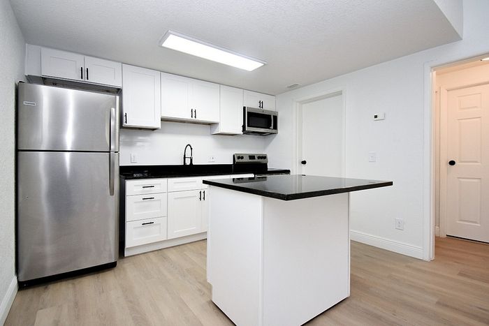 Modern kitchen with sleek stainless steel appliances, elegant black countertops, and ample white cabinetry.