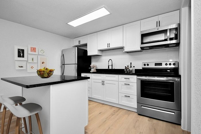 Modern kitchen with sleek white cabinetry, stainless steel appliances, and a stylish breakfast bar featuring comfortable stools.