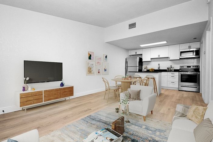 Modern open-plan living area with sleek kitchen, stylish dining space, and cozy lounge. Bright and inviting with contemporary decor.