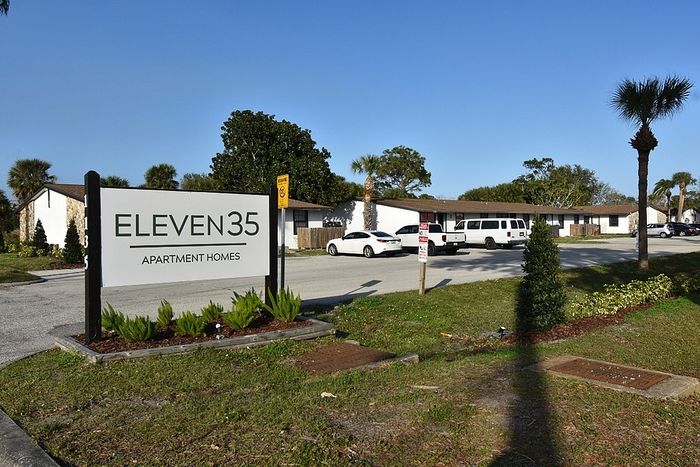 Charming Eleven35 Apartment Homes entrance with lush landscaping and ample parking in a serene neighborhood.