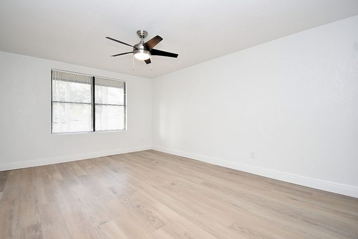 Bright and spacious room featuring sleek modern ceiling fan, large window, and elegant hardwood flooring&mdash;perfect for versatile living.