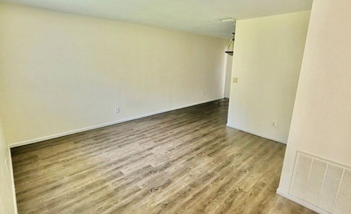 Bright and spacious living area with elegant wood flooring and modern lighting, perfect for entertaining.